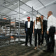 Donald Trump, Kristi Noem, and others walk down a hallway past a prison cell