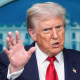 Donald Trump speaks, one hand raised
