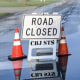 Cones and a road closed sign on a flooded residential street