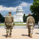 National Guard soldiers walk outside, the U.S. Capitol is seen in the distance