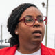 LaMonica McIver walks past a chainlink fence gate outside