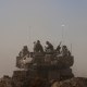Israeli soldiers sit on top of tank parked