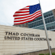 The Thad Cochran United States Courthouse with an American flag at half mast in front of it outside