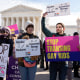 Demonstrators hold signs outside the Supreme Court