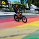 A biker rides through a rainbow-painted crosswalk