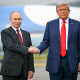 Vladimir Putin and Donald Trump shake hands.