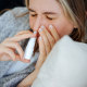 Sick young woman using nasal spray