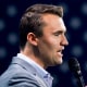 Charlie Kirk speaks on stage, American flag backdrop
