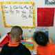 Two children, backs to camera, look at a pre-school decorated wall