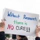 A protesters holds a  sign that reads, "Without Research There Is No Cure" outside the Capitol