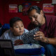 Evan Torres looks at a journal with Robert while seated on a bed