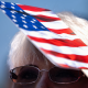 An attendee uses a handheld fan for shade during a naturalization ceremony.