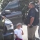 A young girl is surrounded by law enforcement agents outside a house in Leominster, Mass.