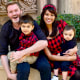 A man and his wife sit on a stoop holding their two young children.