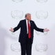 President Donald Trump  stands next to a sign that reads "Peace 2025"