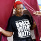 Pamela Evans walks out of a voting booth and is greeted by a poll worker, she wears a black t-shirt that reads "Black Voters Matter" in white lettering