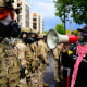 A protester with a bullhorn in front of federal agents.