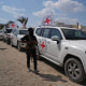 A masked Hamas gunman stands next to Red Cross vehicles arriving for the handover of Israeli hostages by in Khan Younis, southern Gaza Strip, Monday, Oct. 13, 2025.