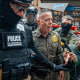 U.S. Border Patrol commander Gregory Bovino pushes through a crowd of media and protesters as he enters the Dirksen Federal Building on Oct. 28, 2025, in Chicago.