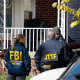 Members of the FBI Joint Terrorism Task Force stand in the front yard as they search a home in Dearborn, Mich., on Oct. 31, 2025. 