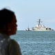 People watch the USS Gravely, a US Navy warship, departing the Port of Port of Spain.