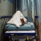 A patient rests in a corridor waiting for a room.