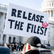 A protester holds a sign related to the release of the Jeffrey Epstein case files outside the Capitol.