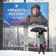 A person walks past a billboard showing a Russian soldier participating in military actions in the Ukraine reading: "The pride of Russia",