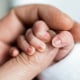 hand of newborn baby who has just been born holding the finger of his father's hand.