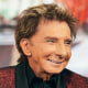 Barry Manilow smiles while seated