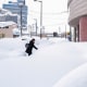 A pedestrian walks on the snow covered pavement 