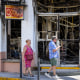 Two people walk past a burnt building