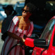 A woman pumps gasoline into her vehicle at a gas station.