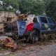 A destroyed SUV draped in a Texas State flag sits next to the road in debris.