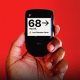 Hand holding glucose monitor that reads "68 mg/dL" 