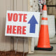 A person walks into a building, signage out front says "vote here"