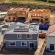 Three partially-built houses stand behind two finished houses with solar panels.