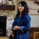 A woman stands in a living room and holds her pregnant belly