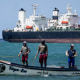 Fishermen pass an oil tanker while on a boat in the water