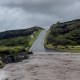 A view of flood waters in the front of a hilly road and grassy planes
