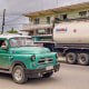 Image: An old American car drives past a truck belonging to a private Cuban company (mipyme) parked in front of a gas station with an IsoTank of imported fuel in Havana