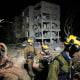 Israeli security forces and rescue teams work at the site struck by an Iranian missile, illuminated by flash at night