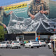 A vendor pushes his cart past a giant billboard reading 'The Strait of Hormuz remains closed' at the Revolution Square in Tehran on April 12.