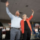 Elizabeth Warren and Graham Platner wave with their arms over each other's shoulders during a campaign event.