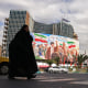 Commuters make their way past a giant billboard of slain Iranian supreme leader Ayatollah Ali Khamenei at the Valiasr Square in Tehran on April 19.