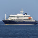 A blue and white cruise ship floats in calm waters under a clear blue sky.