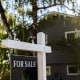 Image: Image of a real estate for sale sign posted in front of a residential home
