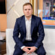Spencer Pratt seated on a white couch with his hands folded in his lap.