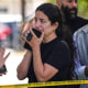 People stand behind police tape at the scene of a shooting