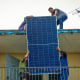 Solar panel specialists lift a panel onto the rooftop of a multi-family building in Matanzas, Cuba, on April 13, 2026. 